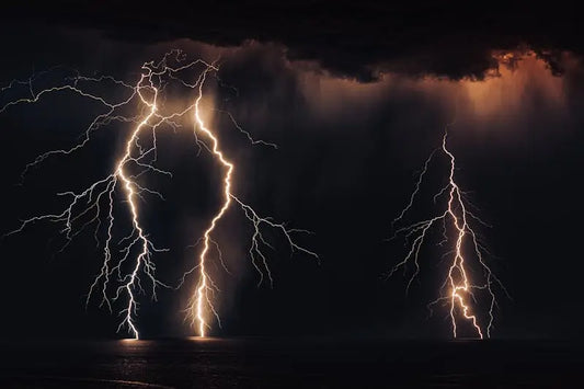 Dark night sky with a thunderstorm, lightning streaking through clouds over a distant horizon, symbolising the soul’s journey through ego death, rupture, and emergence into inner power and spiritual transformation