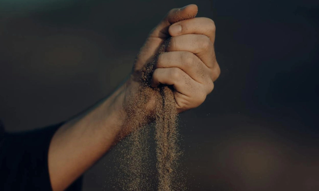 Sand slipping through a man’s hand as he tries to hold it tightly