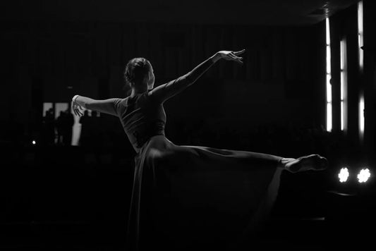 A woman in an elegant black dress gracefully practicing ballet in a studio, a visual metaphor for the patience and discipline required for mastery.