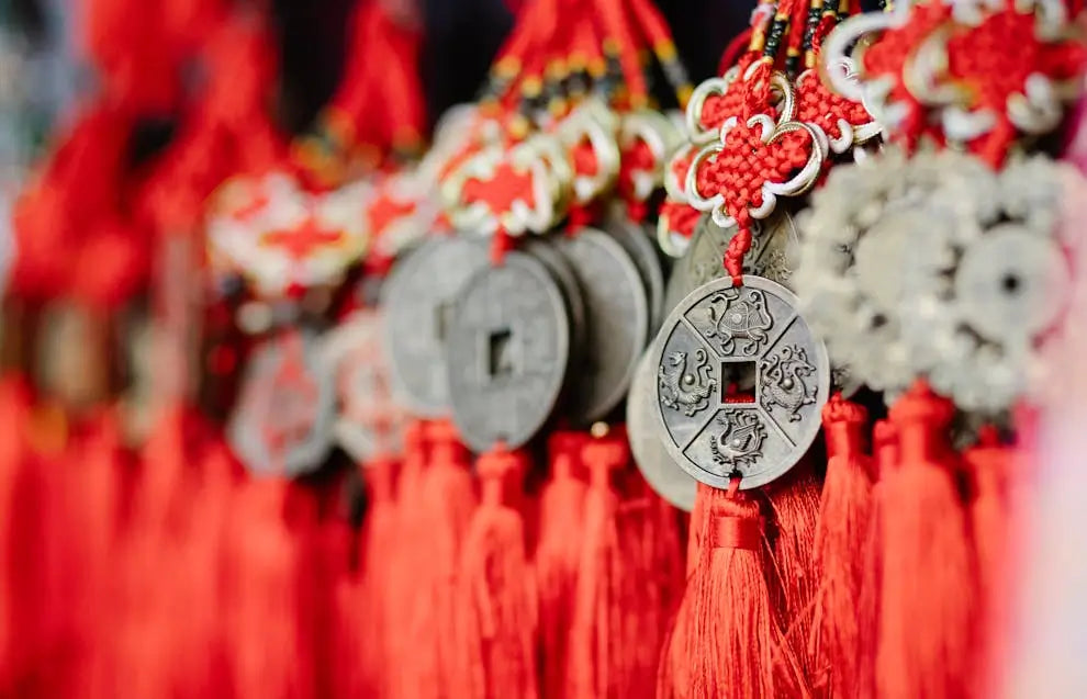 A close-up of several ancient-looking Chinese coins tied together with red knotted ropes and tassels.