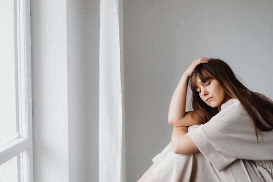 Unmotivated woman sitting by window as if she is lost in life