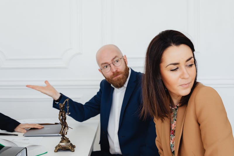 An upset man standing beside a woman in an office, she looks away, showing tension and emotional distance at work
