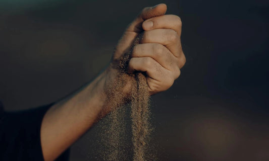 Sand slipping through a man’s hand as he tries to hold it tightly